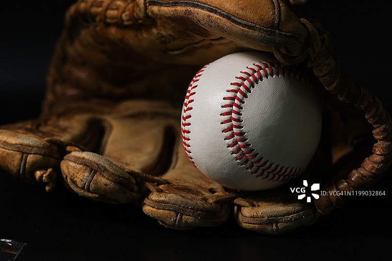 黑色背景上的手套和棒球图片素材