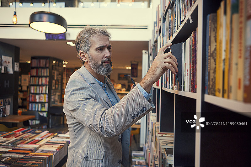 男人在书店里从书架上取书图片素材
