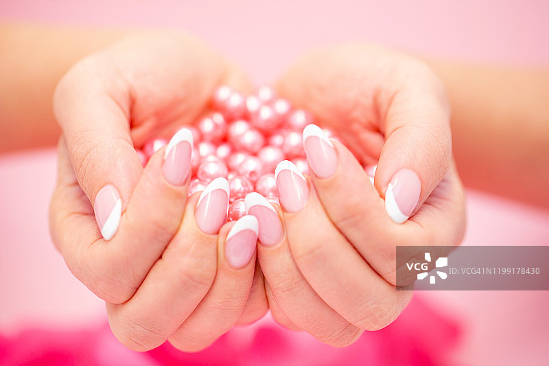 做过法式美甲的手拿着粉色珍珠图片素材