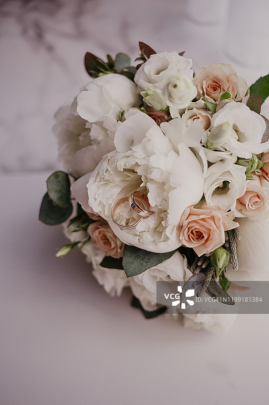 婚礼花束上的2枚金戒指，配有美丽的玫瑰和芍药。婚礼当天。婚礼准备图片素材