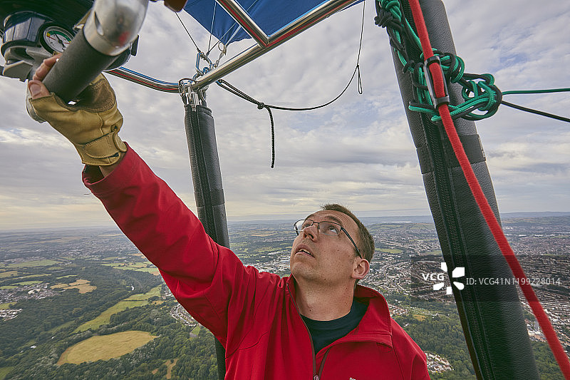 热气球飞行员在英国布里斯托国际气球节期间调整燃烧气体喷嘴，为气球内部的空气加热图片素材