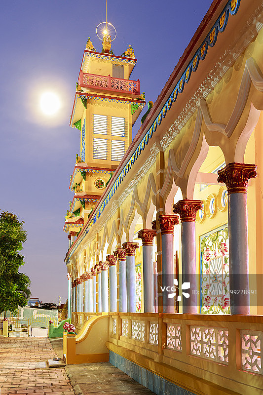 越南头顿高台寺：塔楼沐浴在暮色中，满月悬挂于左侧图片素材