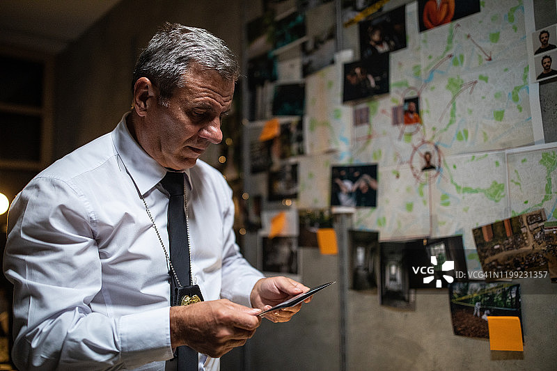 年长的警探在墙前查看罪犯照片图片素材