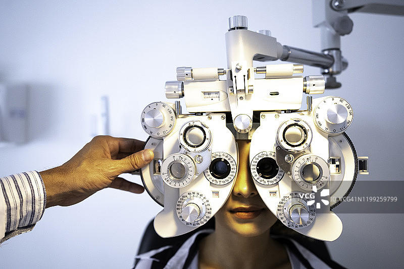 女士在眼科诊所用光学焦度计测量视力图片素材