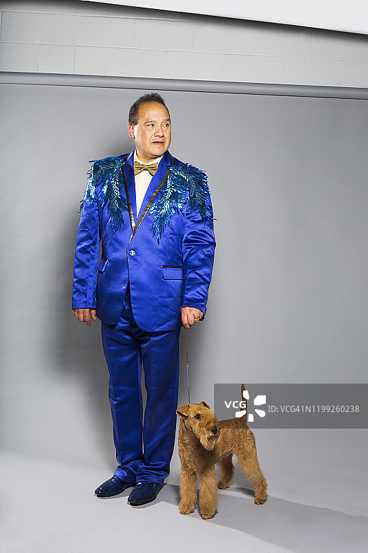 穿着蓝色西装的拉丁裔男子和湖畔梗犬图片素材