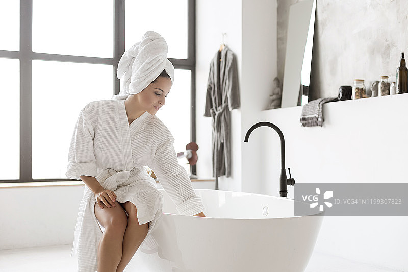 年轻女士身穿浴袍触摸水面图片素材
