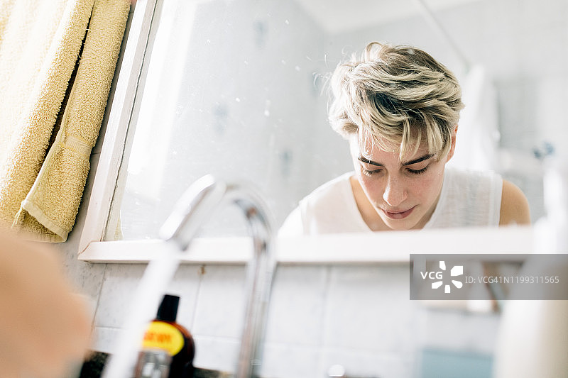 在浴室水槽上洗脸的女人图片素材