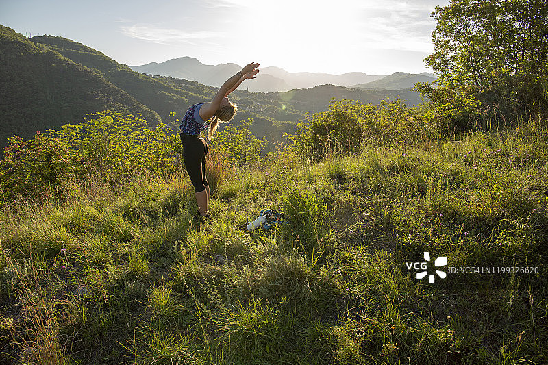 年轻女人在山间草地做瑜伽动作图片素材