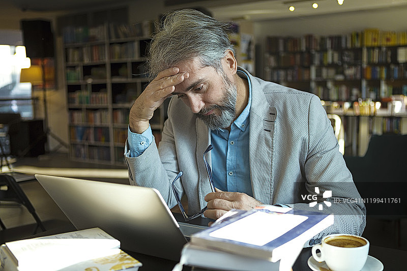 中年男子使用笔记本电脑学习遇到困难图片素材