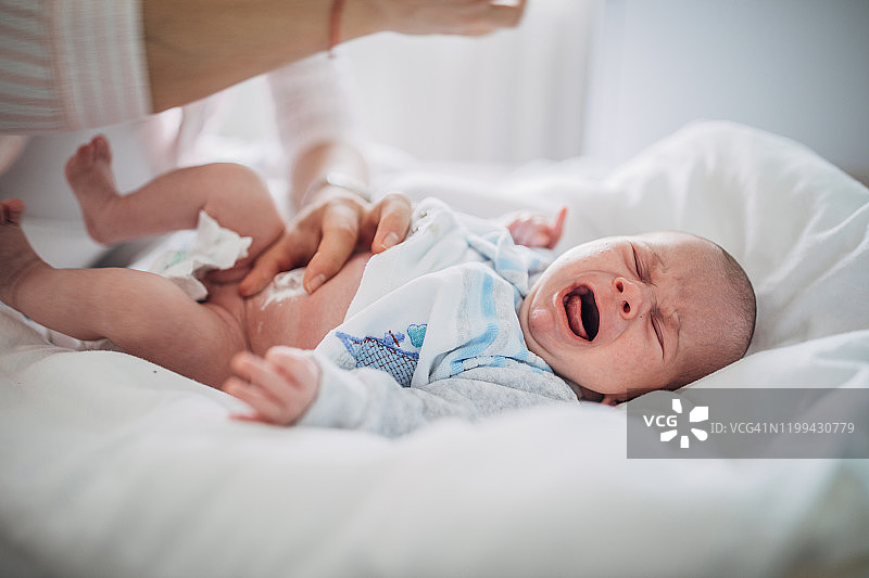 母亲清洁新生男婴的肚脐图片素材