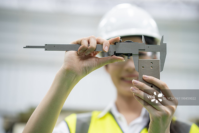 女工程师用专用卡尺测量并验证制造钢零件的精度图片素材