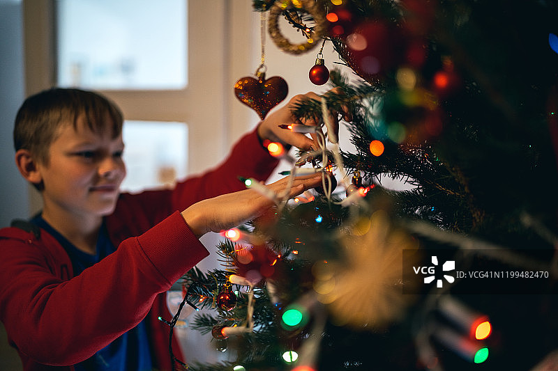 男孩在家装饰圣诞树图片素材