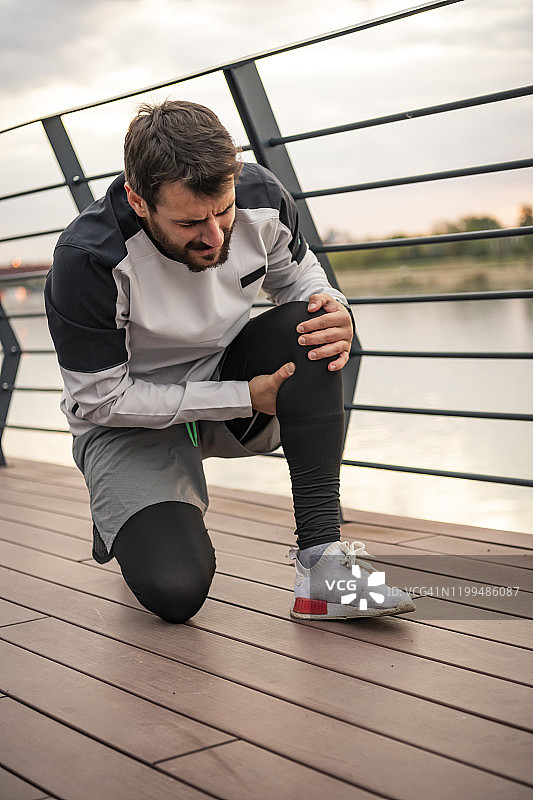 练习中膝盖受伤的年轻帅气的运动员图片素材