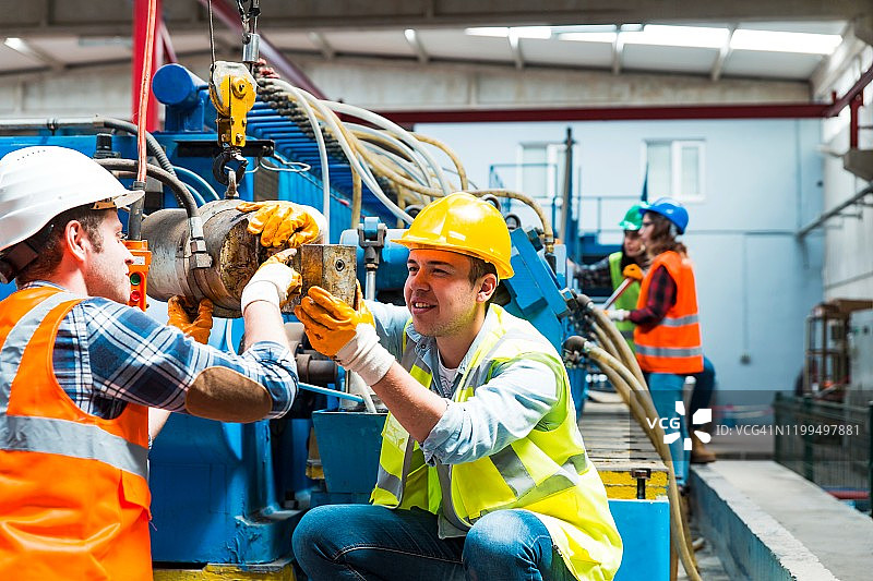 在工厂里使用电缆卷的年轻产业男女工人图片素材