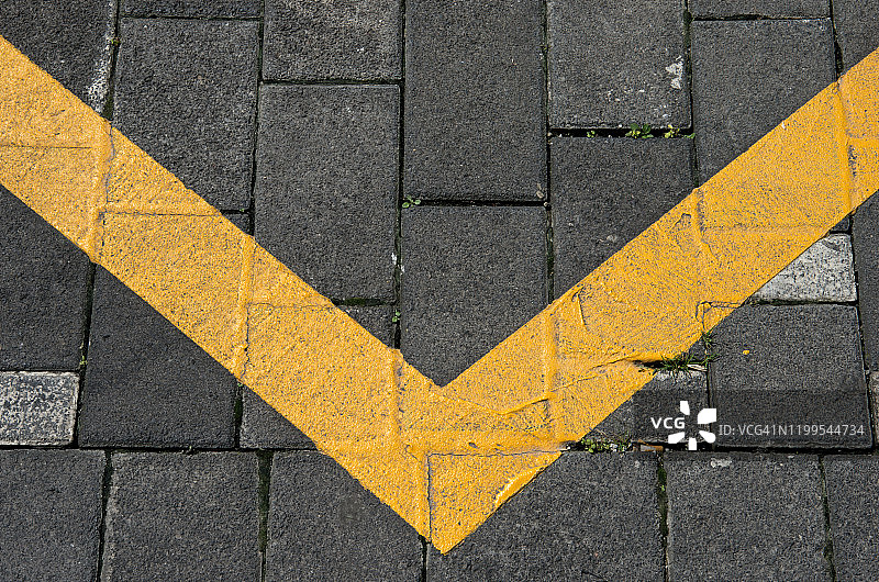 灰色铺路石上黄色油漆V形线图片素材