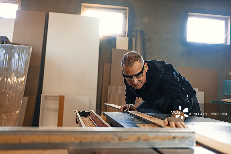 年长的男性木匠在他的工作室里工作图片素材