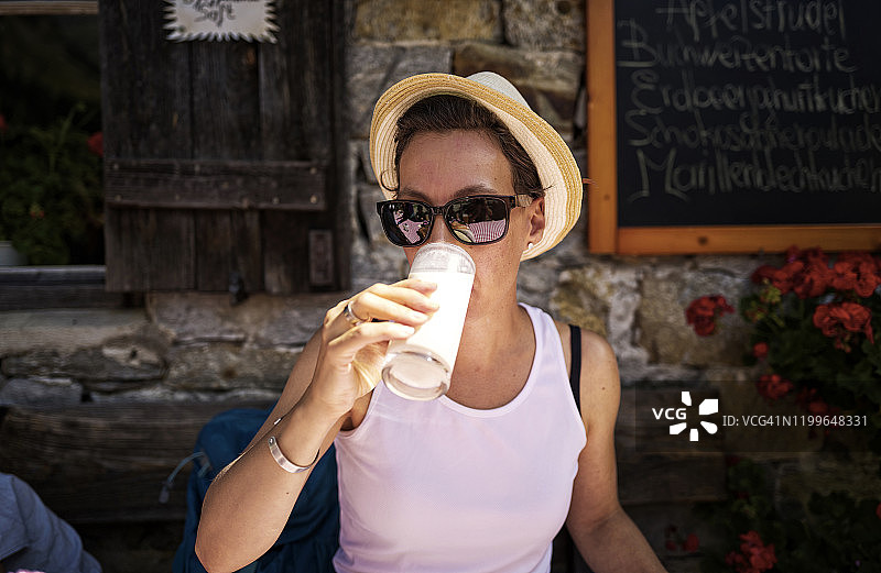 女子在意大利南蒂罗尔山间小屋享受一杯酪乳图片素材