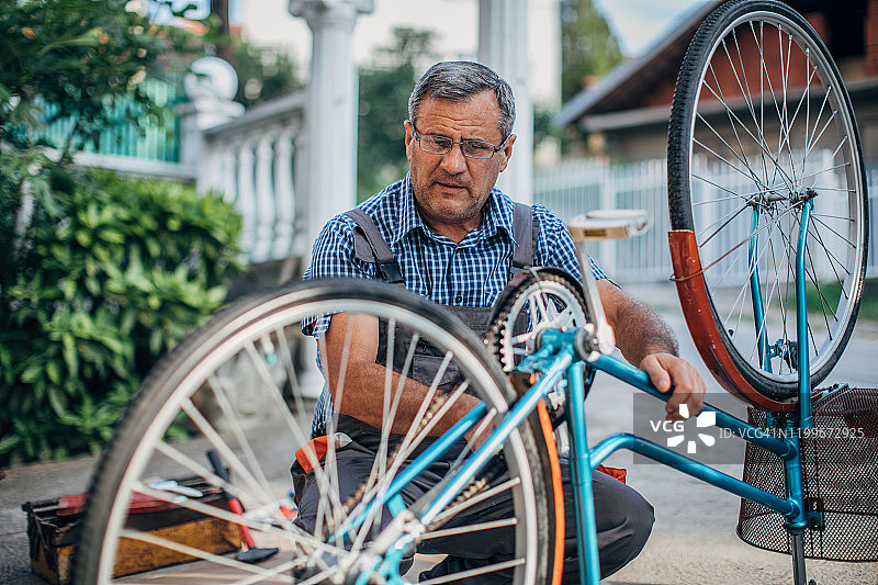 年长的男人修理自行车图片素材