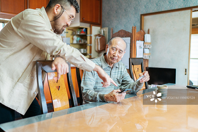 男人帮助爷爷网上购物图片素材