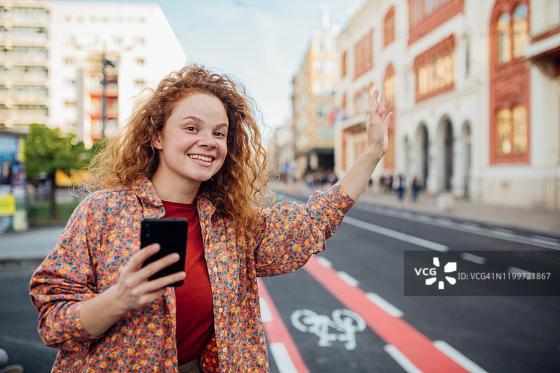 美丽的红发女孩招手拦出租车图片素材