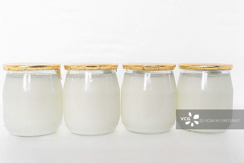 白色背景下的玻璃罐装希腊酸奶和勺子图片素材