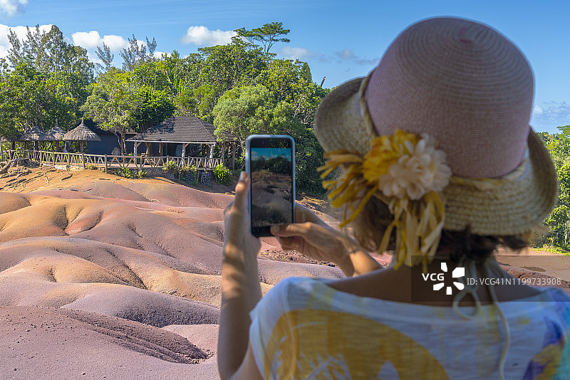 女人用手机拍摄毛里求斯七色土图片素材