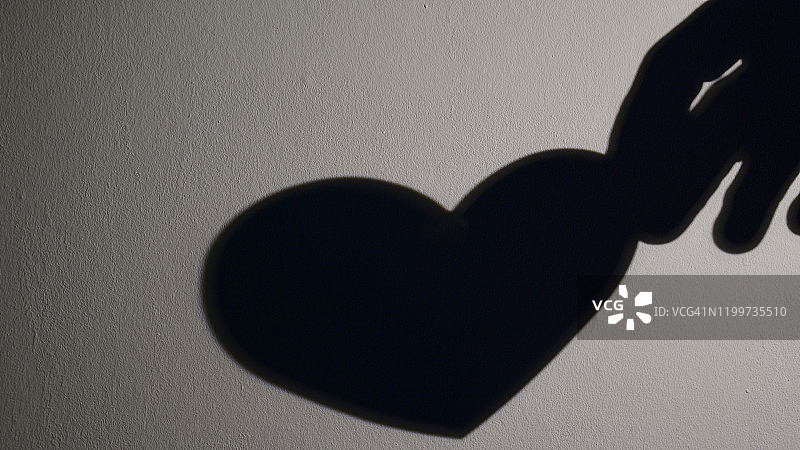 手持心形墙壁阴影图片素材