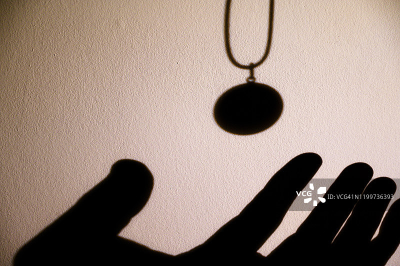 即将抓住吊坠的人手剪影图片素材