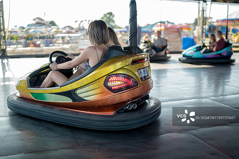 快乐的女友们驾驶碰碰车并微笑图片素材