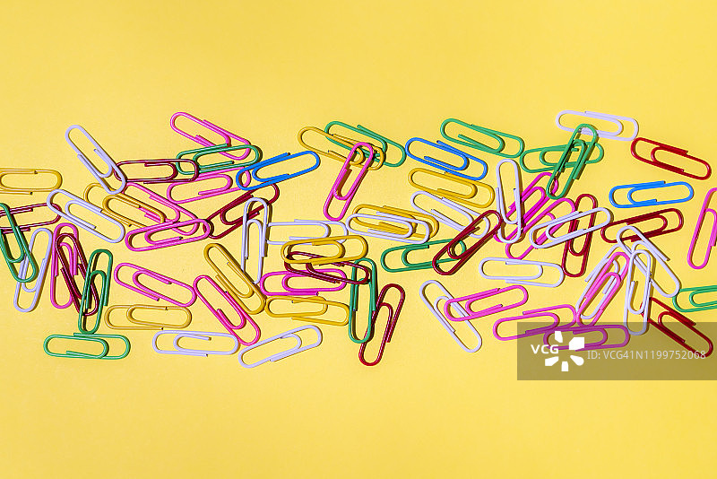 黄色背景上的彩色回形针图片素材