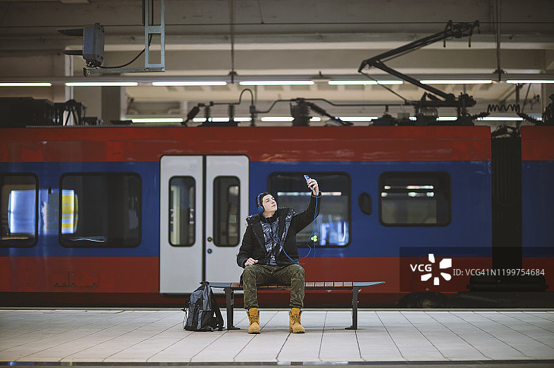 在地铁站听音乐和自拍的青少年男孩图片素材