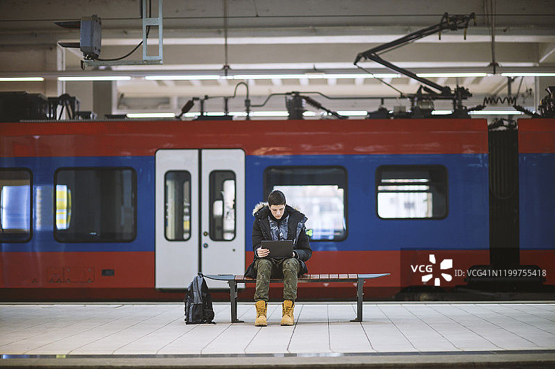 在地铁站使用笔记本的青少年男孩图片素材