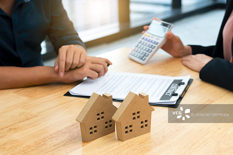 房产中介在办公室向客户讲解利率并展示计算器图片素材