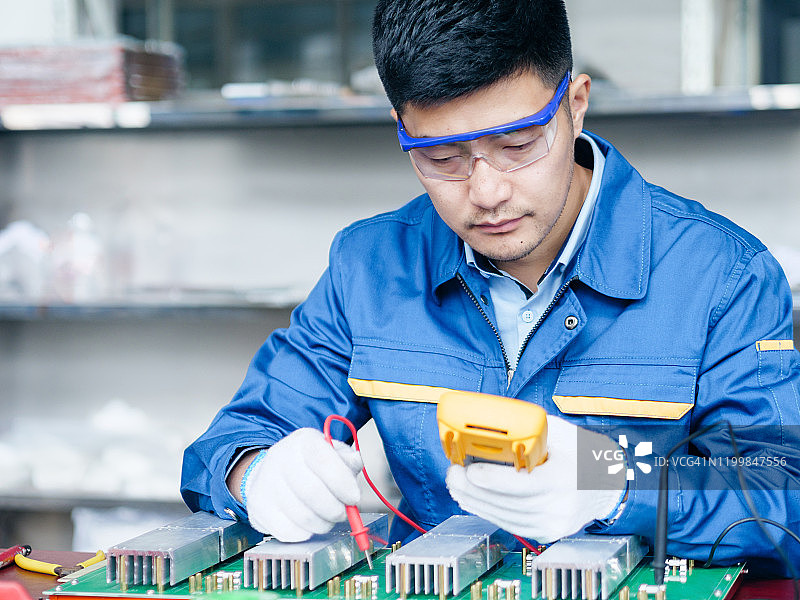 年轻亚洲维修人员用数字万用表检查电压图片素材