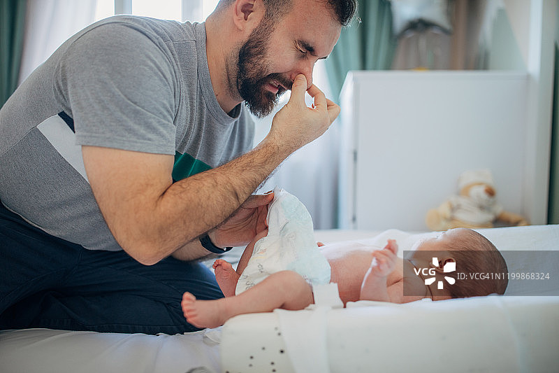 父亲在家给男婴换尿布图片素材