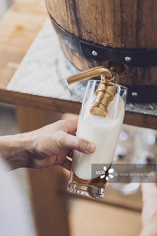 男人从桶里往玻璃杯里倒啤酒的特写图片素材