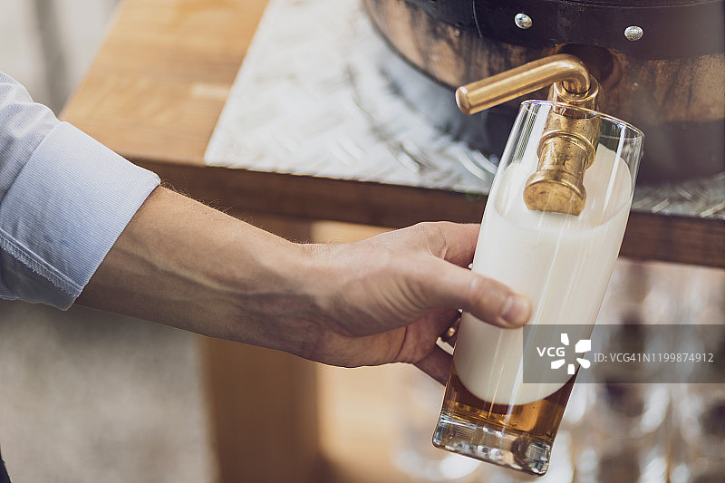 男人将啤酒从木桶倒入玻璃杯特写图片素材