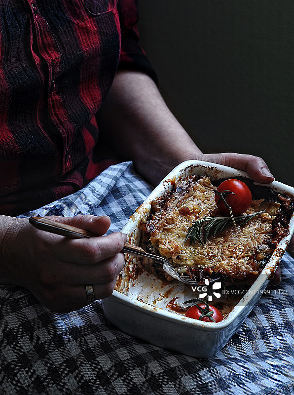 手中的自制意大利千层面，在低调的家庭风格中吃到一半图片素材