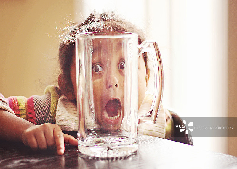 站在玻璃杯后做鬼脸的女孩肖像图片素材