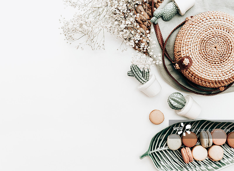 叶形盘子上的马卡龙，鲜花、仙人掌装饰，白色背景图片素材