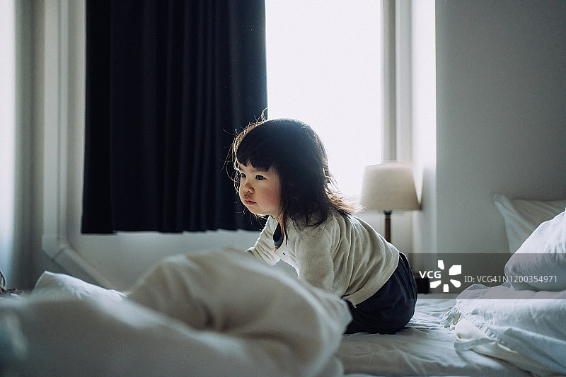 可爱的小女孩清晨醒来后坐在床上图片素材