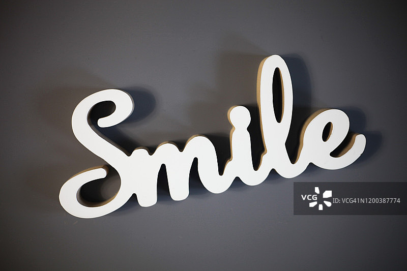 灰色背景上的木制“微笑”字样图片素材