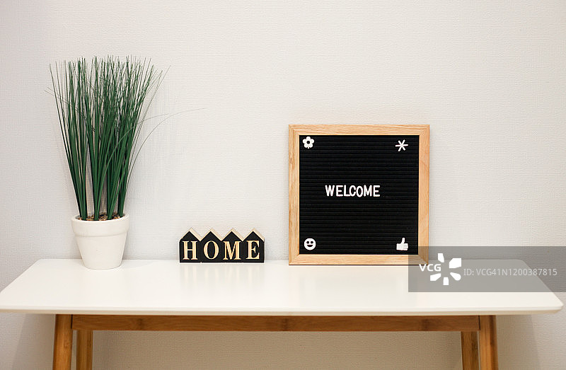 桌上的家居室内细节：盆栽花卉与木制单词“Home”图片素材