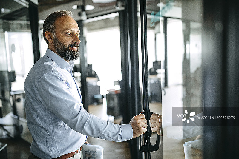 在办公室门口拿着报告的商人图片素材