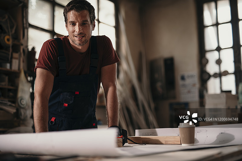 年轻木匠在车间制作家具时分析设计方案图片素材