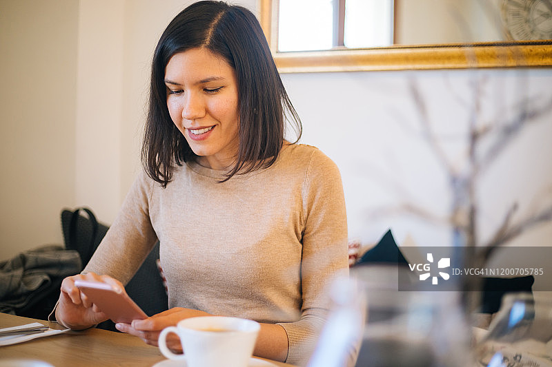 在咖啡馆使用智能手机的漂亮女人图片素材