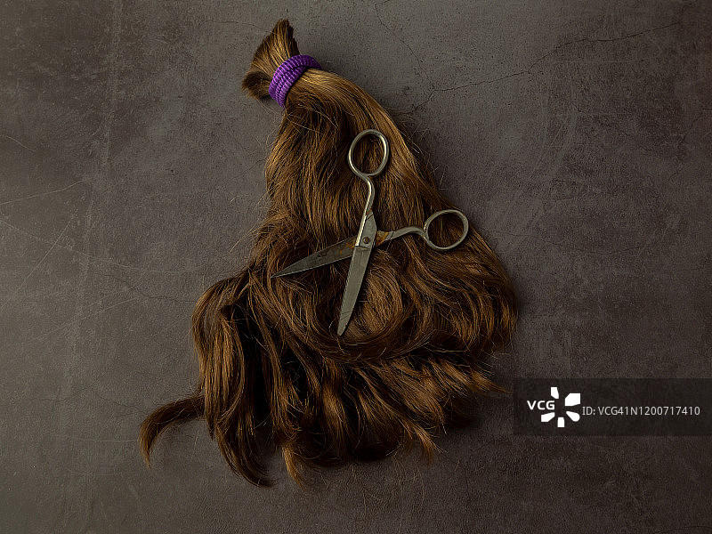 复古风格：紫色橡皮筋扎着一束金发，背景为灰色和旧剪刀图片素材