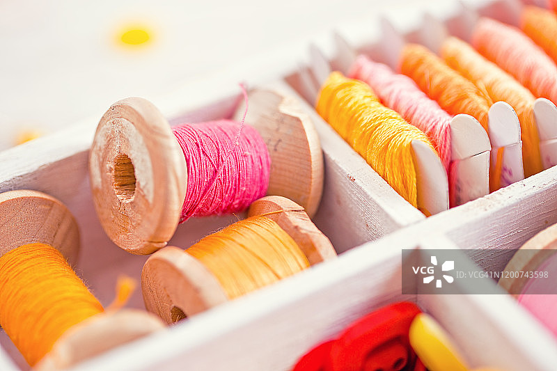 装有黄色、红色、粉色线轴的缝纫盒特写图片素材