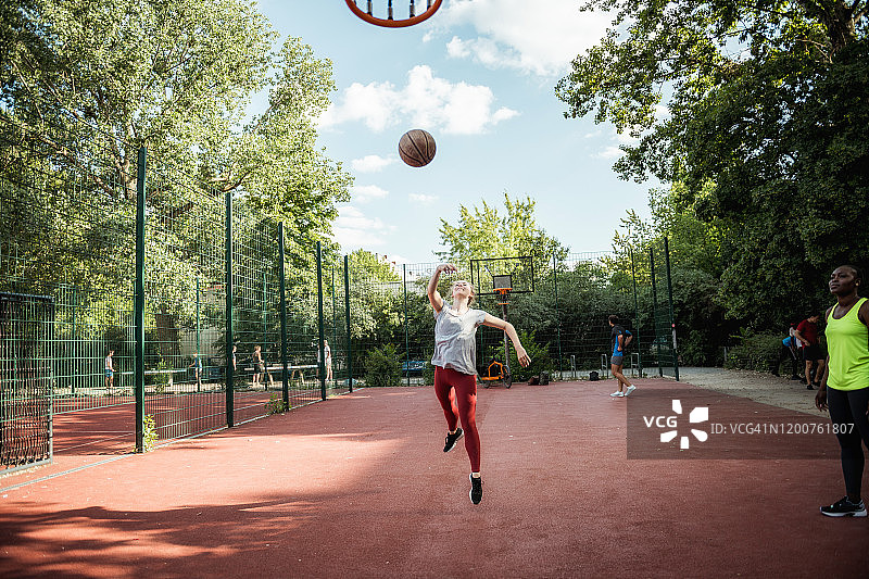 年轻女人在硬地球场打篮球图片素材
