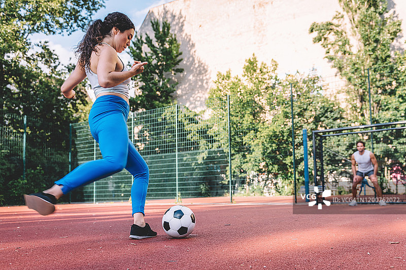 年轻女运动员在足球门上踢点球图片素材